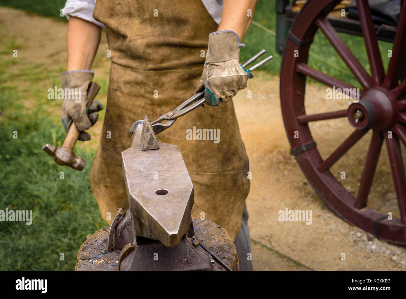 Fabbro lavora su un oggetto di ferro con un martello durante un workshop. Foto Stock