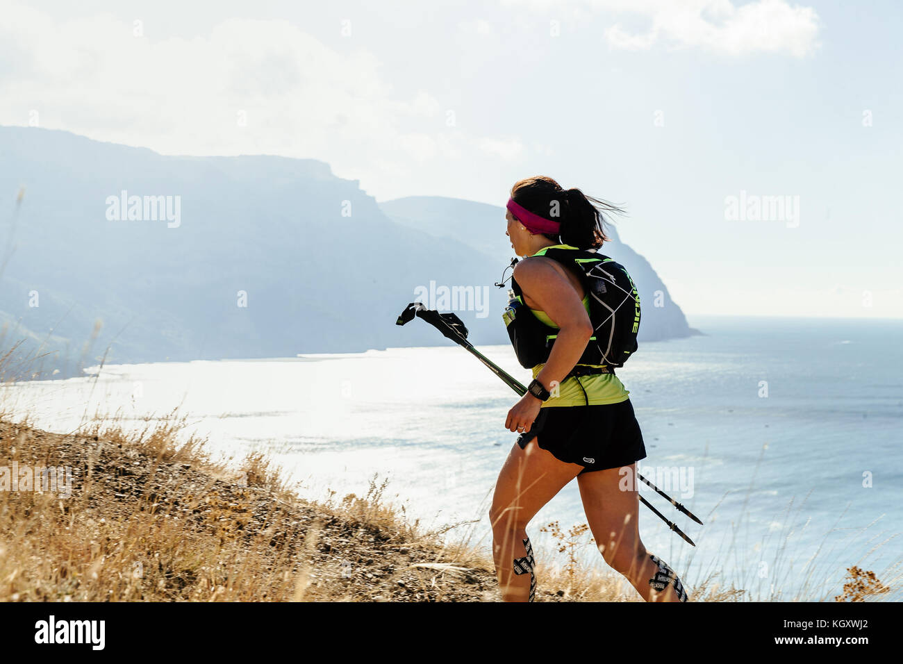 Ragazza runner con pali trekking che eseguono montagna sentiero del mare durante la Crimea х eseguire Foto Stock
