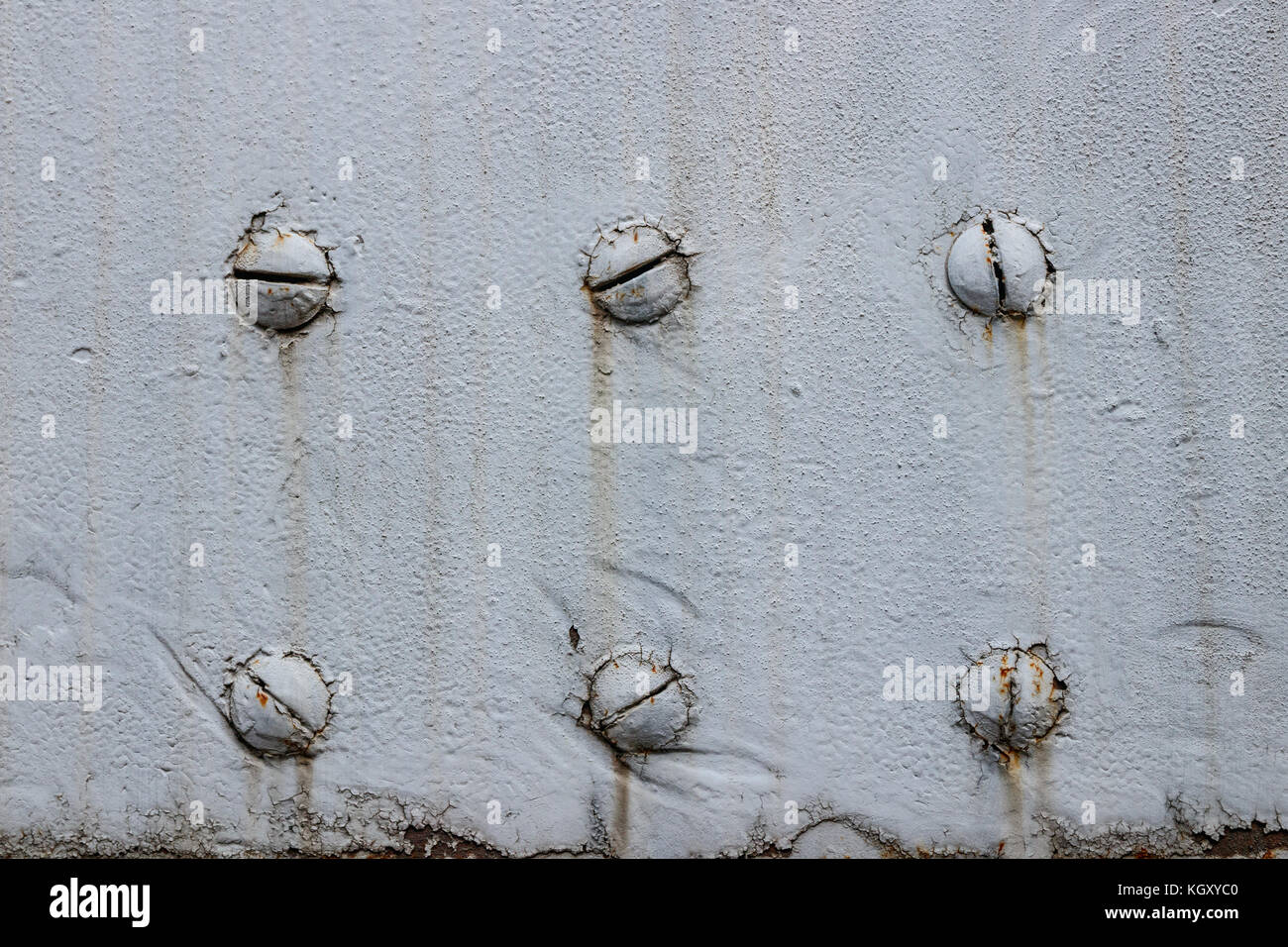 Close-up di sei viti in una superficie metallica ricoperta con il grigio, weathered vernice. Foto Stock