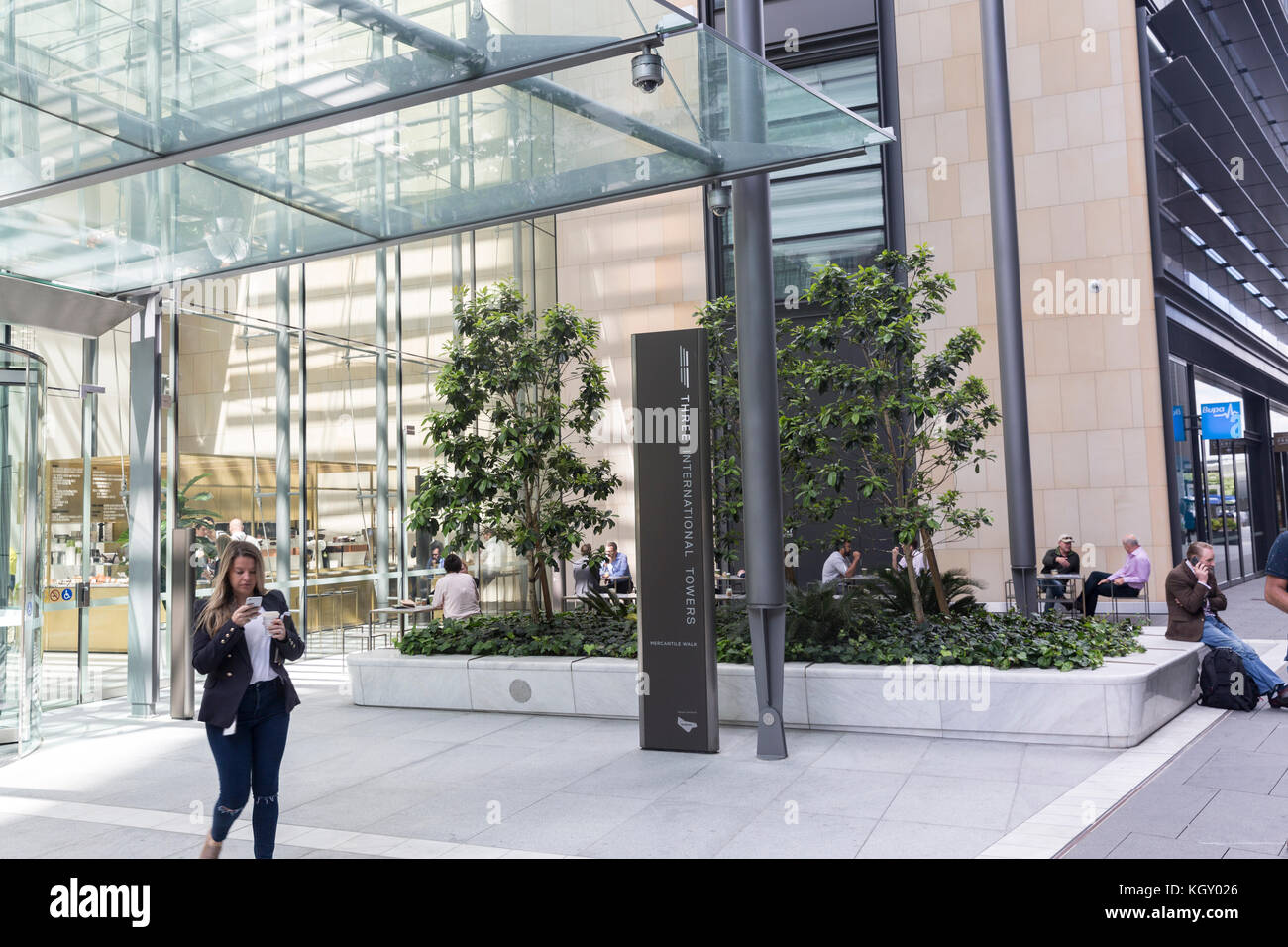 Femmina di lavoratore di ufficio su telefono lasciando tre torri internazionale edificio al molo di Barangaroo di Sydney , Australia Foto Stock