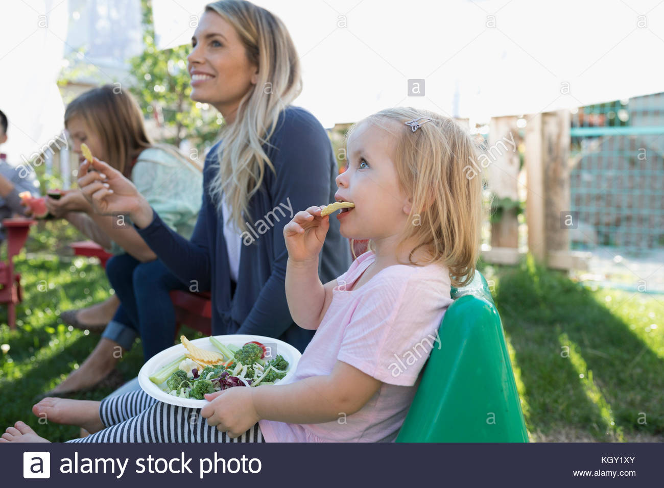 Madre e figlia dei bimbi di mangiare al barbecue nel cortile Foto Stock