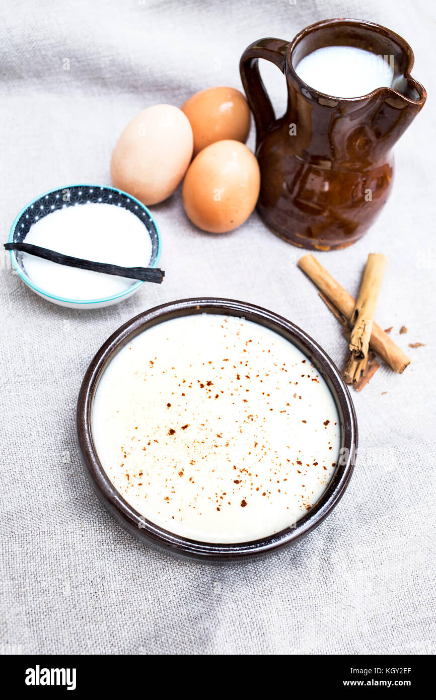 Una gustosa crema dessert con gli ingredienti con cui esso è realizzato come zucchero, uova, latte e bastoncini di cannella Foto Stock