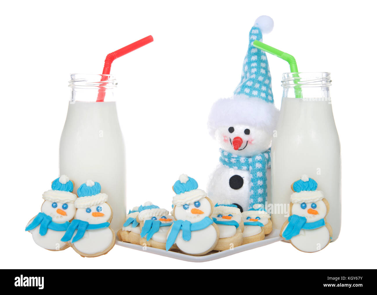 Pupazzi di neve lo zucchero i cookie con blue sciarpe e soffice blu e bianco cappelli su una piastra con bottiglie di latte di colore verde e rosso cannucce. più pupazzi di neve cookie stand Foto Stock