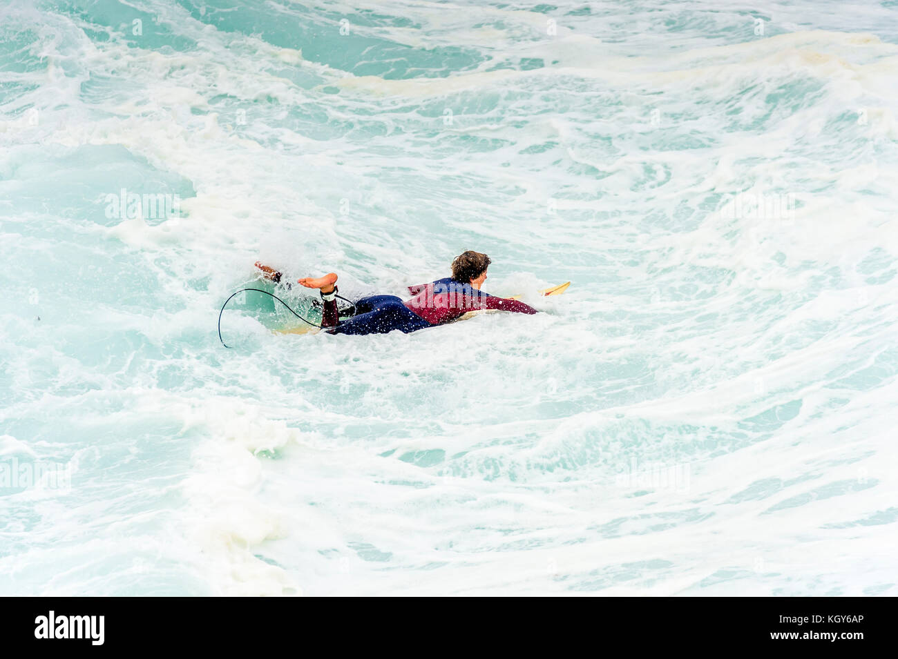 Un surfista pagaie fuori attraverso la zangolatura acqua in pericolose condizioni di surf a Bronte Beach a Sydney, NSW, Australia Foto Stock