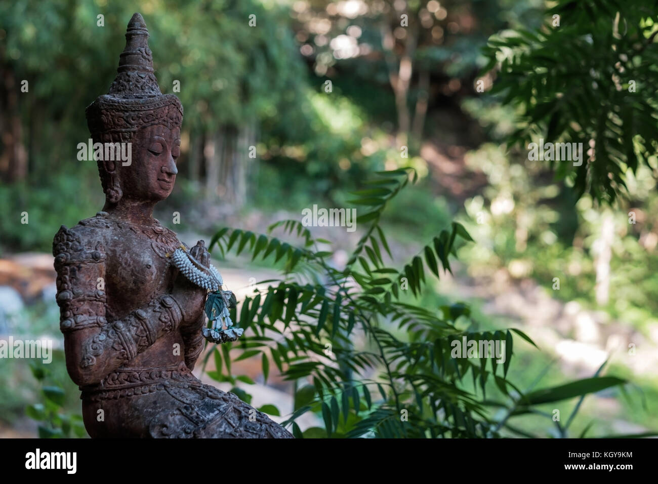 Un'antica statua di Buddha meditando sullo sfondo di un verde della foresta o giungla. Foto Stock