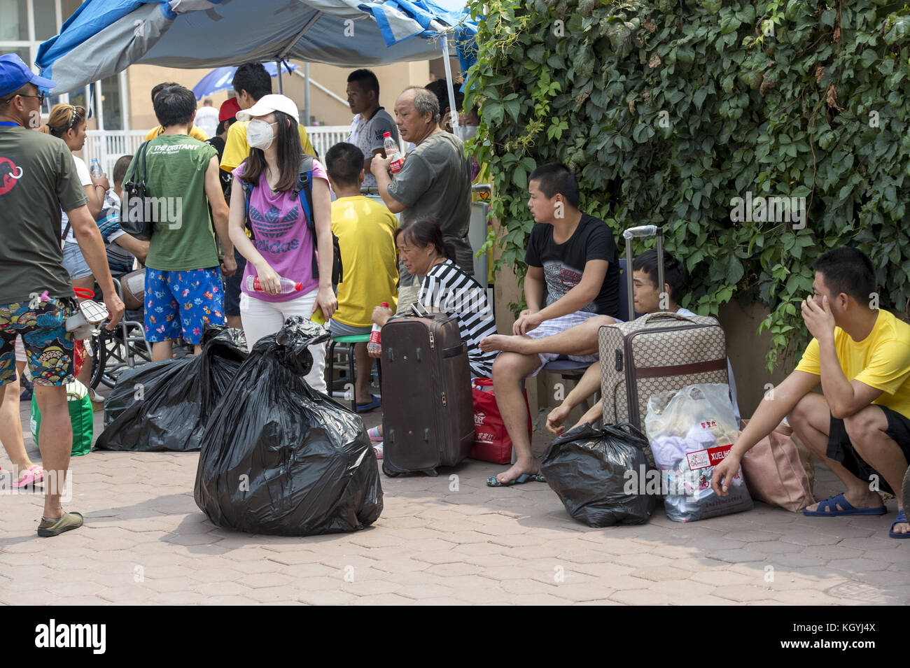 Tianjin, Cina. 17 agosto 2015. Dopo l'esplosione di Tianjin. Le persone si riuniscono intorno al campo scolastico per arrivare lì carte d'identità temporanee, in quanto sono costrette dal governo a lasciare la città senza soldi, ma con un biglietto per la loro provincia. Signora Wu, 52 anni, camicia a righe bianco e nero. Lavoratore immigrato di Hubei. Siamo venuti qui per avere un documento temporaneo per tornare a casa in Hubei. Il governatore ci ha comprato i biglietti del treno. Vivevamo in questo campo prima, ma ci hanno evacuati in molti altri posti. Penso che il governatore ci darebbe un risarcimento, no? non abbiamo mangiato niente da ieri sera. non c'è abbastanza cibo. Foto Stock