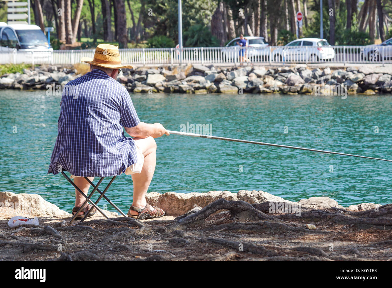 Senior pensionati uomo gode di pesca da un molo nel fiume Foto Stock