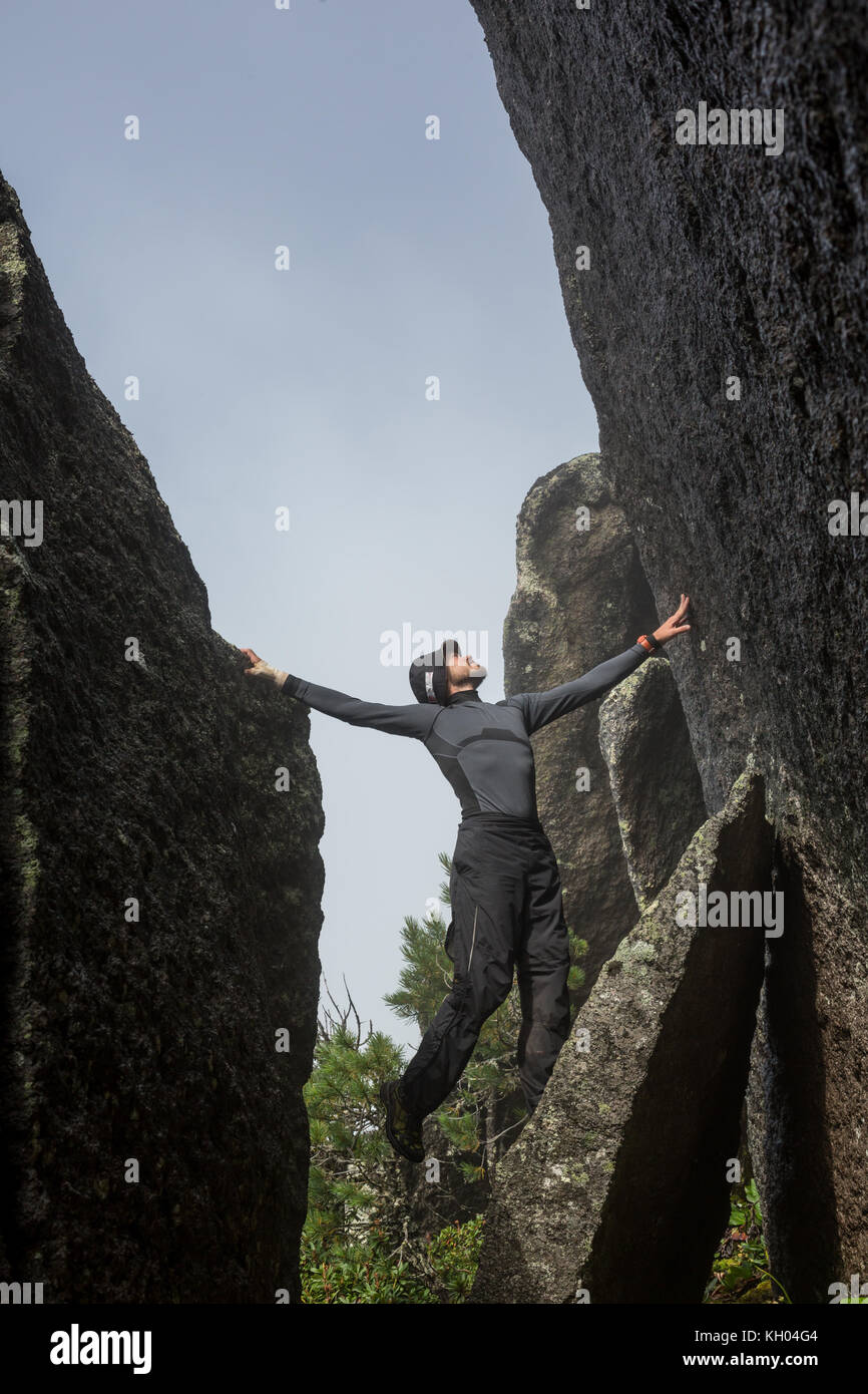 Maschio di rocciatore. rocciatore si arrampica su un nero parete rocciosa sull'oceano banca in Islanda, kirkjufjara beach. l uomo rende difficile muoversi senza fune. Foto Stock