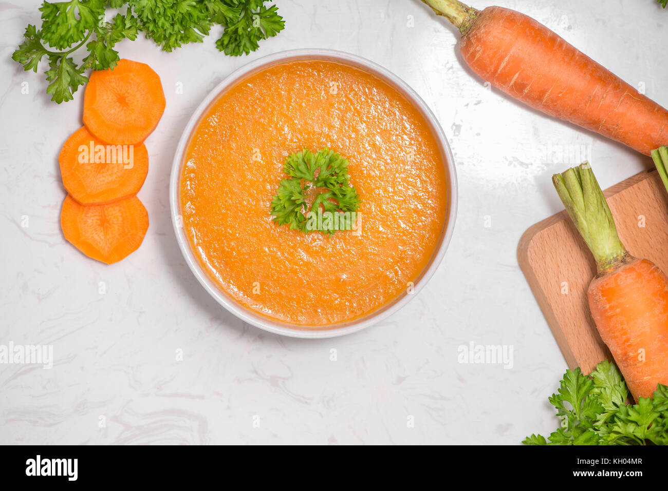 Zuppa di carote con panna e prezzemolo sulla pietra bianca sfondo. vista dall'alto. spazio copia Foto Stock