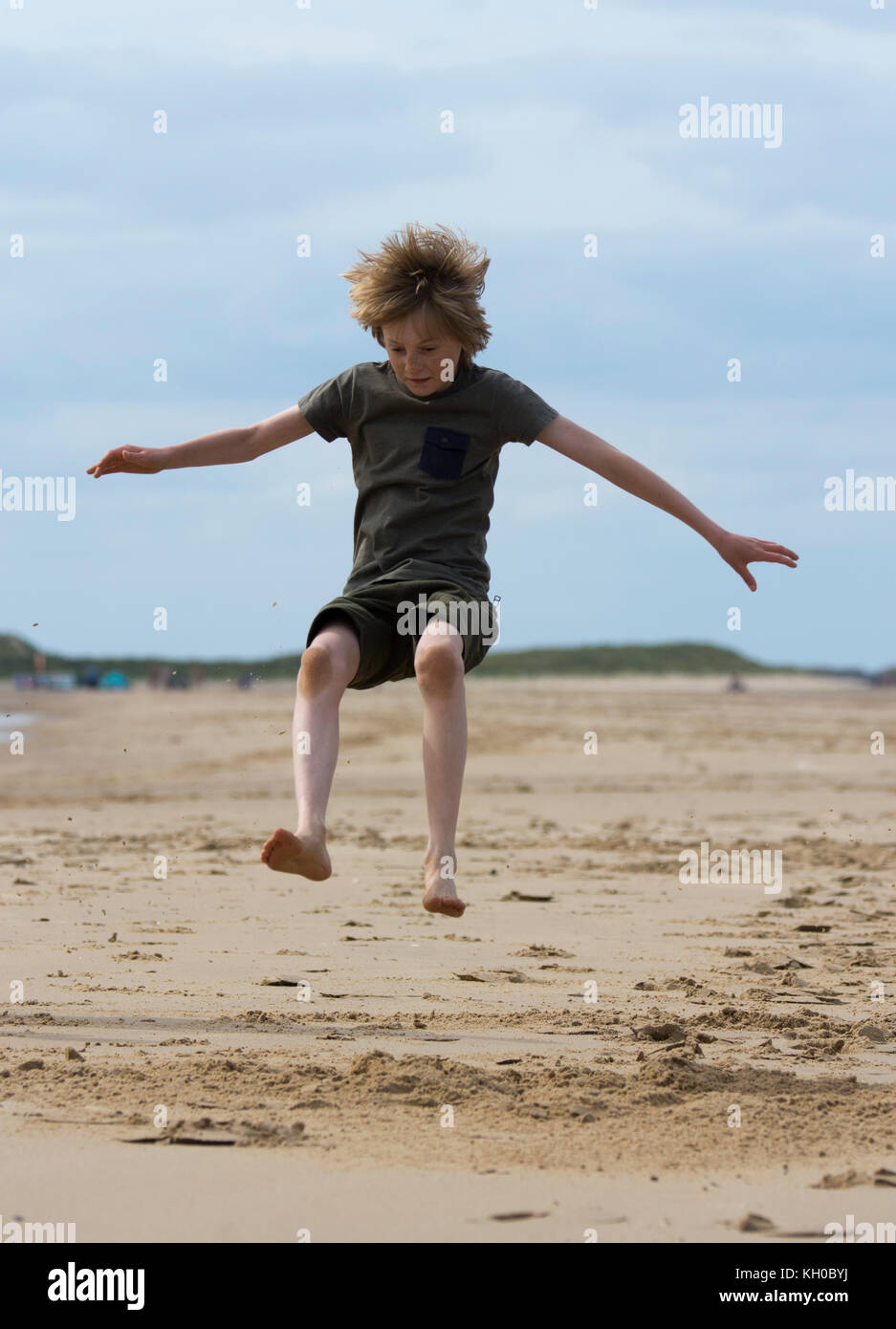 Ragazzo in midair facendo il salto in lungo su una spiaggia Foto Stock