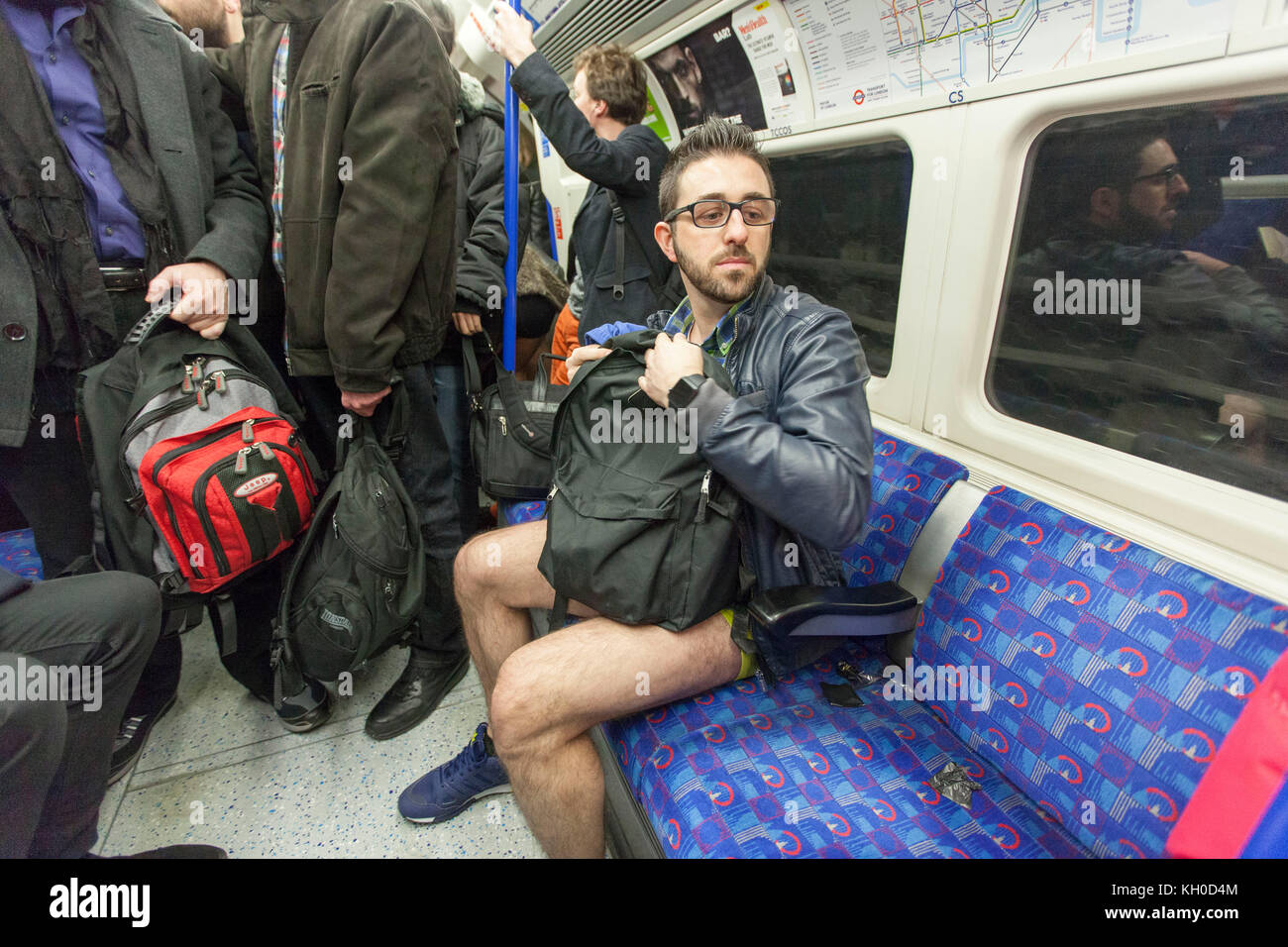 Un uomo è seduto in una stazione della metropolitana di Londra senza i pantaloni e accanto ad altri passeggeri come se fosse la cosa più naturale. Foto Stock