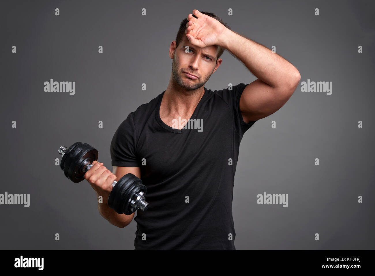 Un bel giovane uomo peso di sollevamento e sensazione di stanchezza Foto Stock