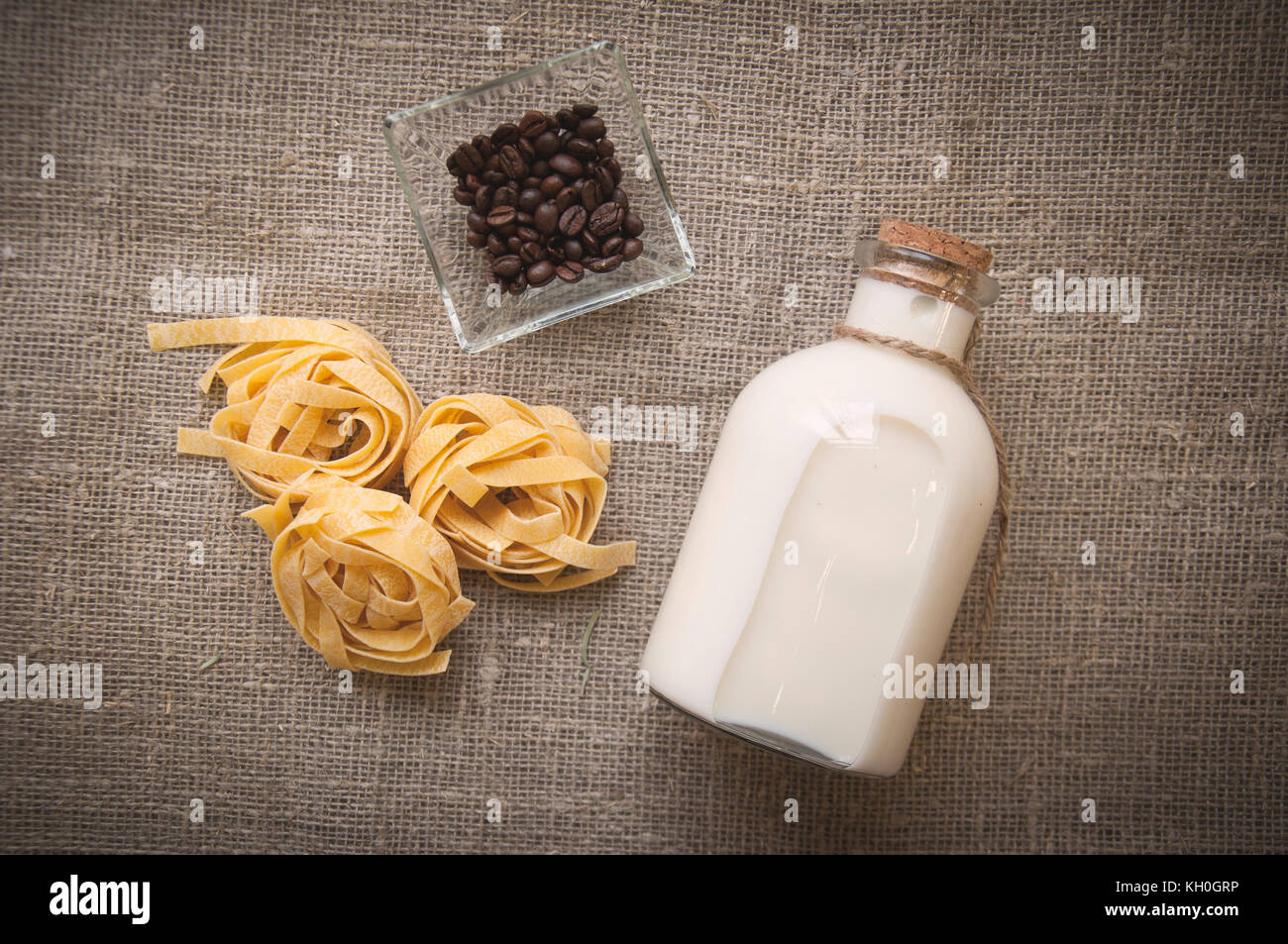 Bottiglia di latte crudo, fettuccine e chicchi di caffè Foto Stock