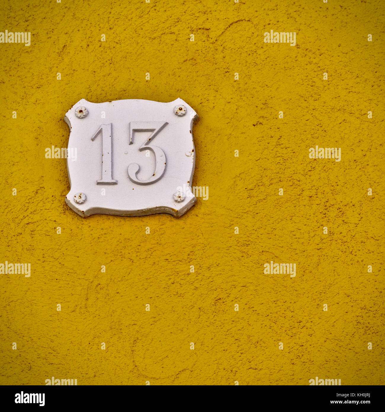 Numero 13,numero 13 in bianco su una parete di colore giallo con un vecchio e tessitura grossolana Foto Stock