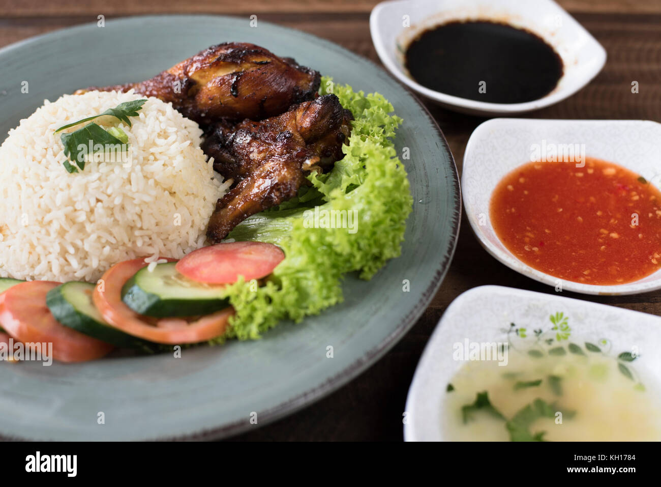 Popolari piatto malese nasi ayam o pollo con riso cotto pollo a pezzi, pomodoro, cetriolo, insalata, zuppa, la salsa di soia e salsa di peperoncino. Foto Stock