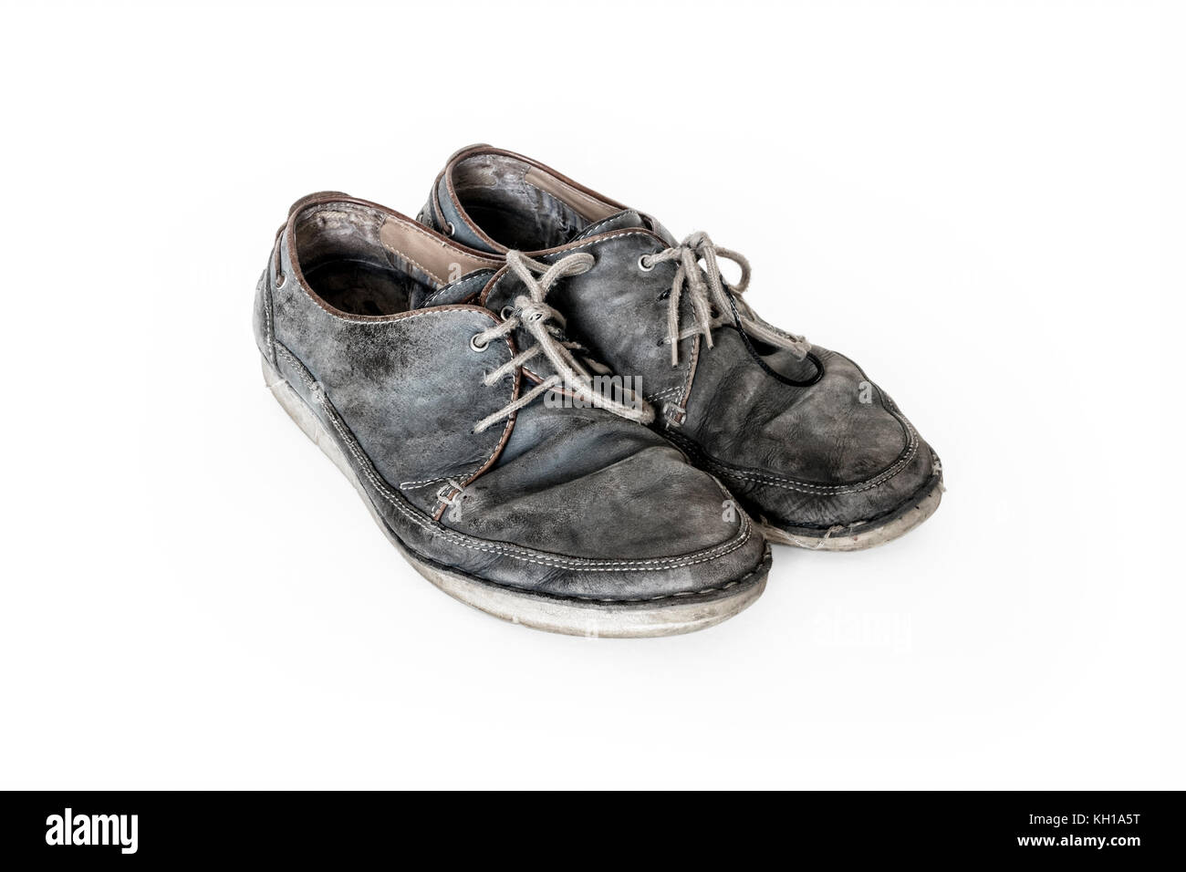 Una coppia di vecchi usurato in pelle grigio scarpe con lacci contro uno sfondo bianco Foto Stock