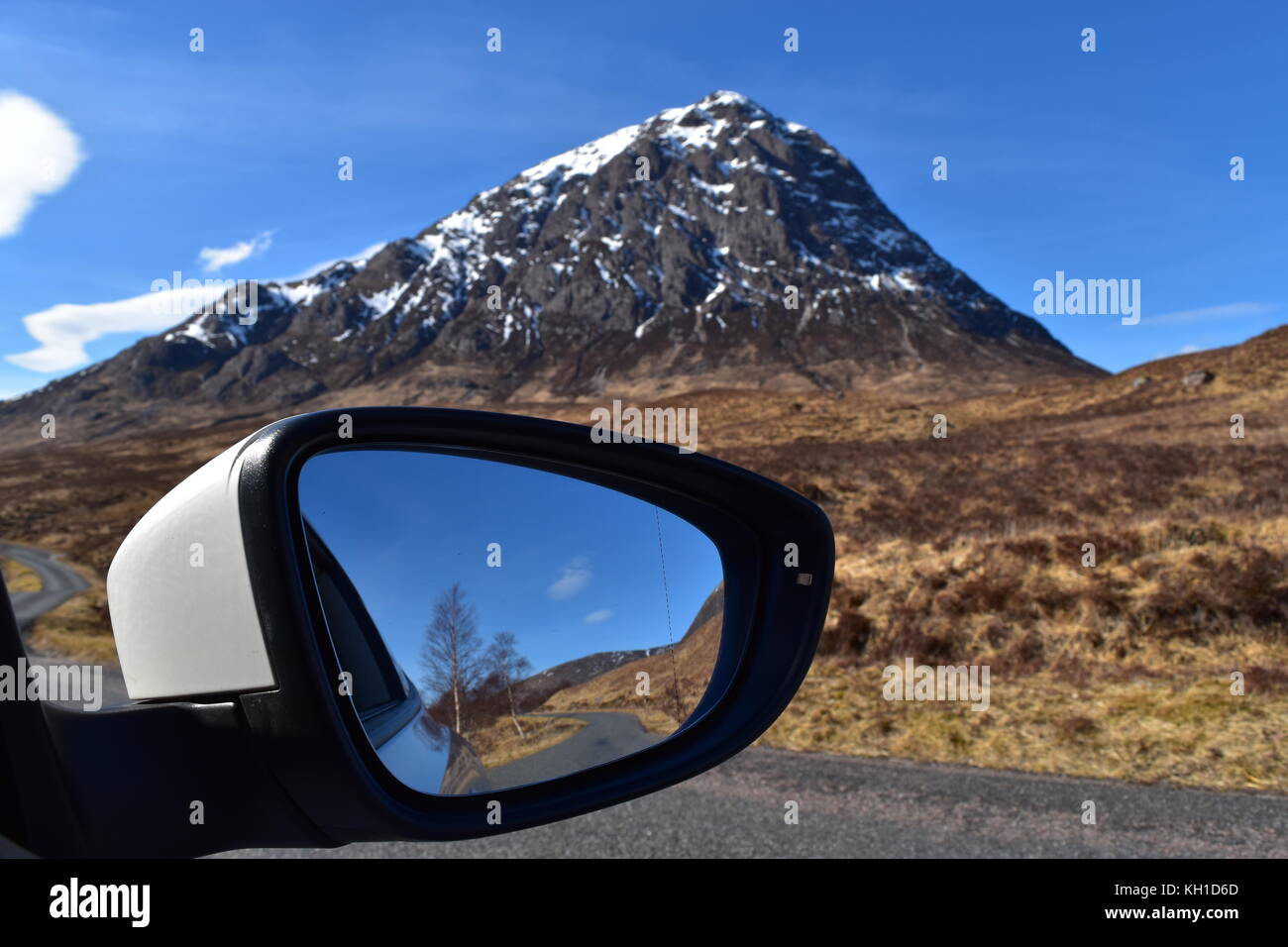 Snow capped Buchaille Etive mor con il trasporto su strada si riflette nell'ala specchio dell'auto. Glen Etive, Scozia. Foto Stock