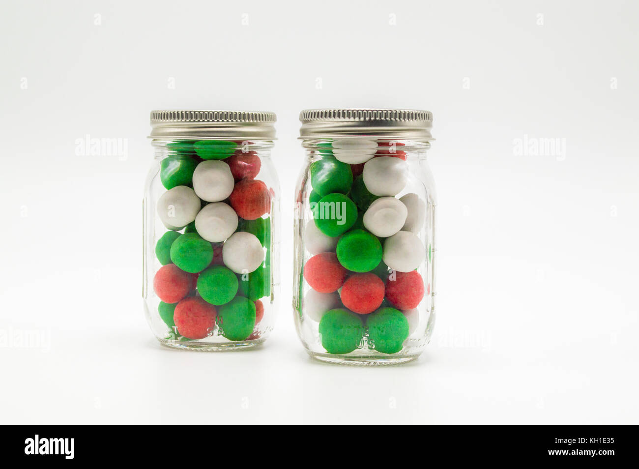 Natale colorate candy in 2 piccoli vasetti di vetro isolato su uno sfondo a tinta unita Foto Stock