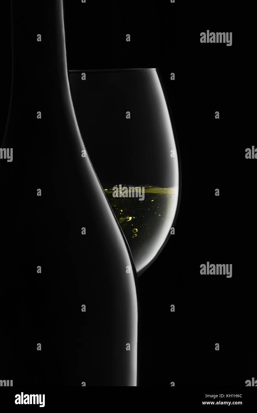 Bottiglia e bicchiere di vino bianco su sfondo nero Foto Stock