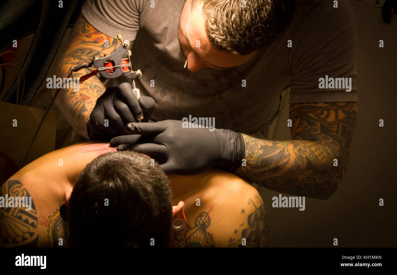 Un tatuaggio artista attinge il suo ritorno a un giovane ragazzo.----------Milano, mi, Italia - 9 febbraio 2013: un tatuaggio artista attinge il suo ritorno a un ragazzo durante un tatuaggio Foto Stock