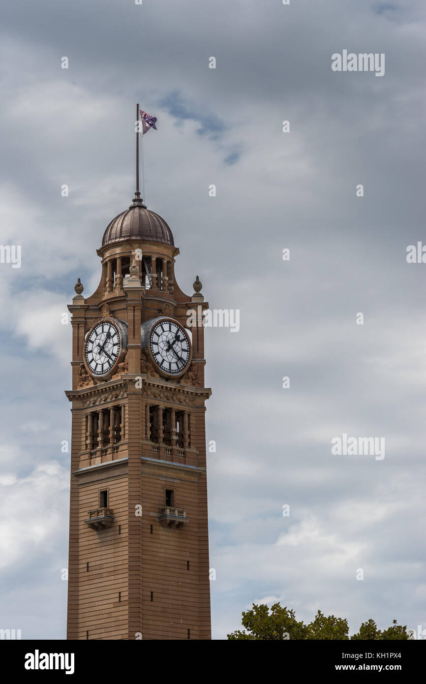 Sydney, Australia - 25 marzo 2017: vista dettagliata della parte superiore della pietra marrone stazione ferroviaria torre dell orologio contro il cielo pesante. bandiera sulla parte superiore. Foto Stock