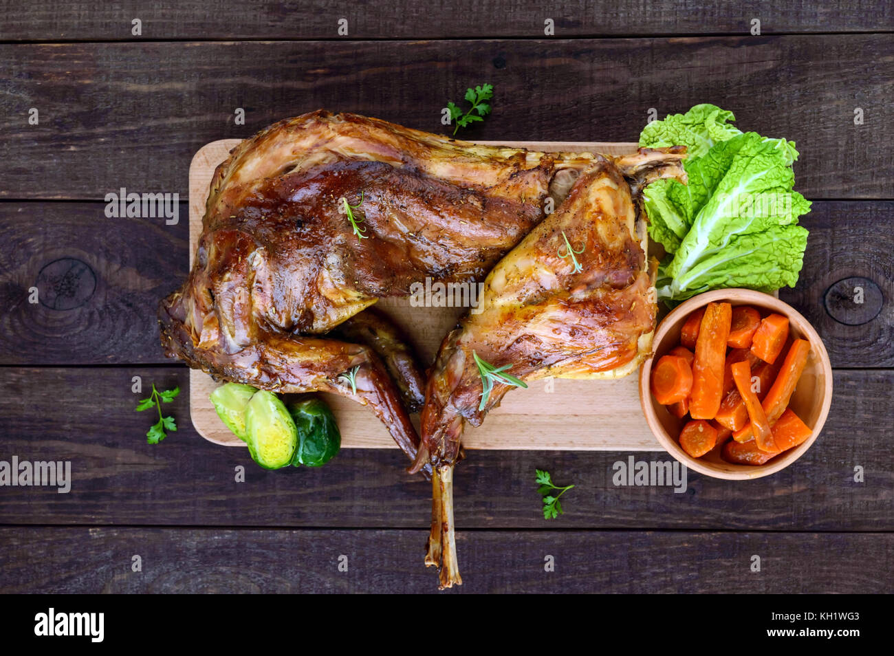 Arrosto di coniglio intero su una tavola di legno con carote al forno e  cavolini di Bruxelles su uno sfondo scuro. Un pasto di festa. La vista  dall'alto Foto stock - Alamy
