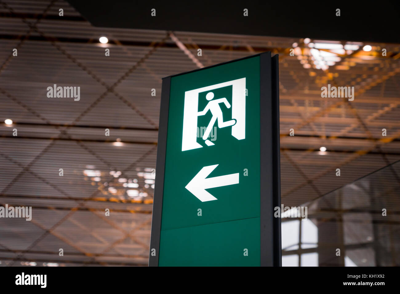 Emergency fire exit segno verde brillante in aeroporto Foto Stock