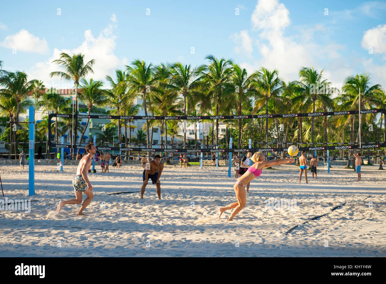 MIAMI - 31 agosto 2017: Una donna atletica scava un po' mentre gioca a pallavolo sul lungomare di Miami Beach con lo sfondo dell'iconico edificio art-deco Foto Stock