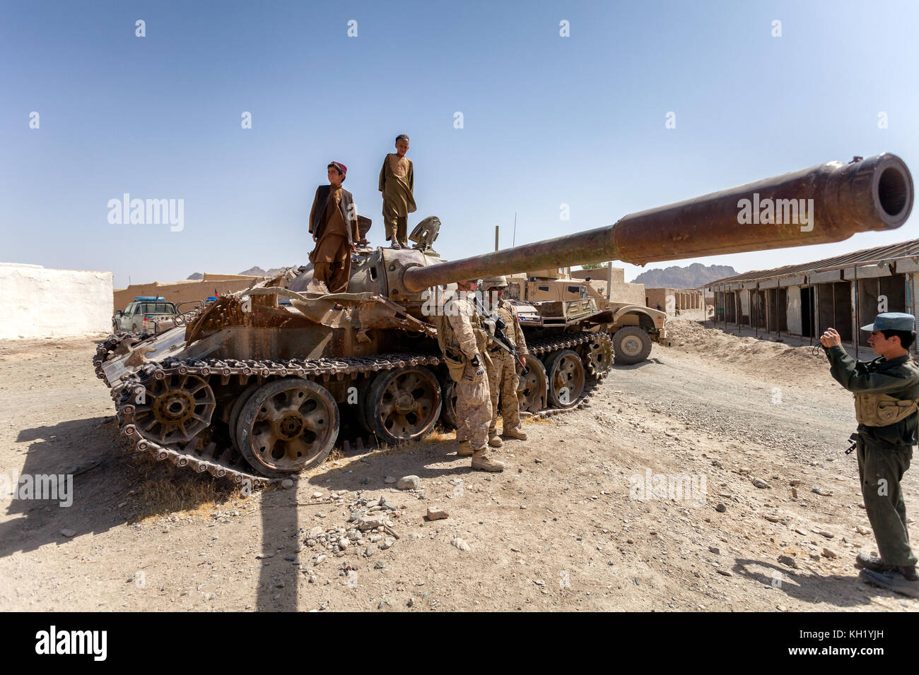 I Marines DEGLI STATI UNITI posano per le immagini vicino al carro armato russo vecchio lasciato sopra dall'occupazione russa nella città di Nowzad, provincia di Helmand, Afghanistan Foto Stock
