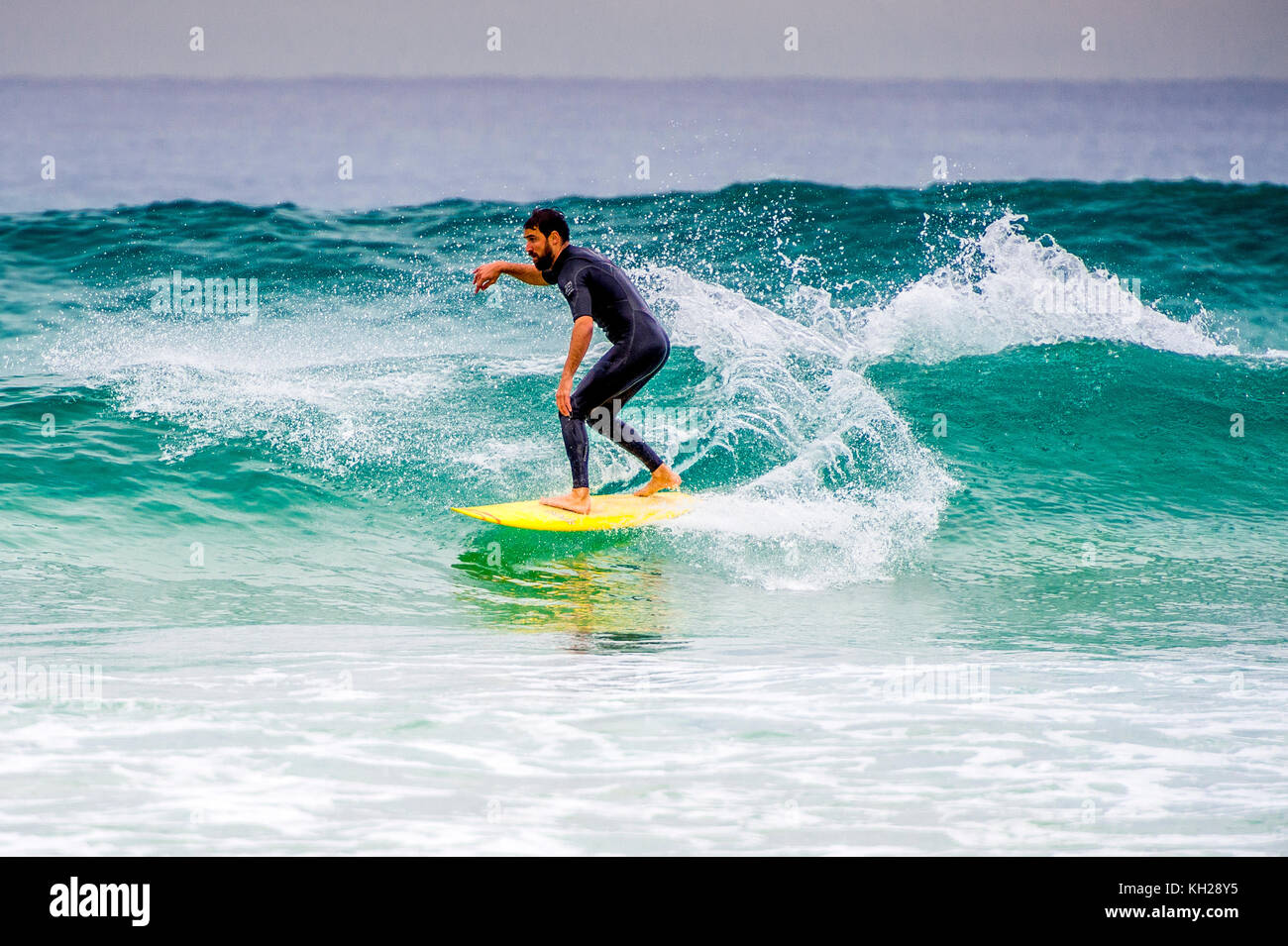 Un surfista cavalcare un onda a Sydney iconici Bondi Beach, NSW, Australia Foto Stock