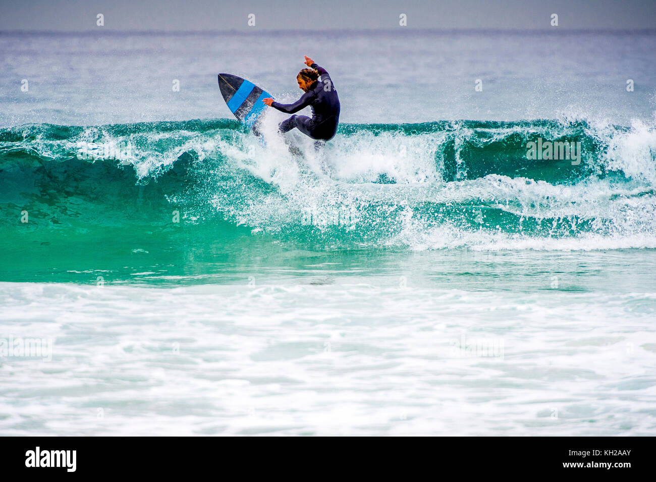 Un surfista cavalcare un onda a Sydney iconici Bondi Beach, NSW, Australia Foto Stock