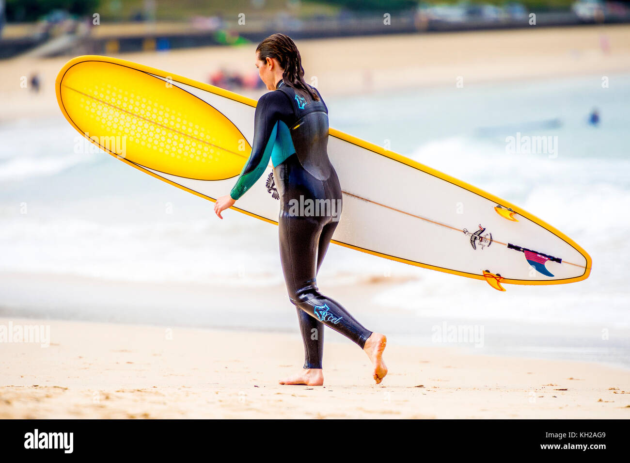 Un surfista femmina esce dall'acqua a Bondi Beach a Sydney, NSW, Australia Foto Stock