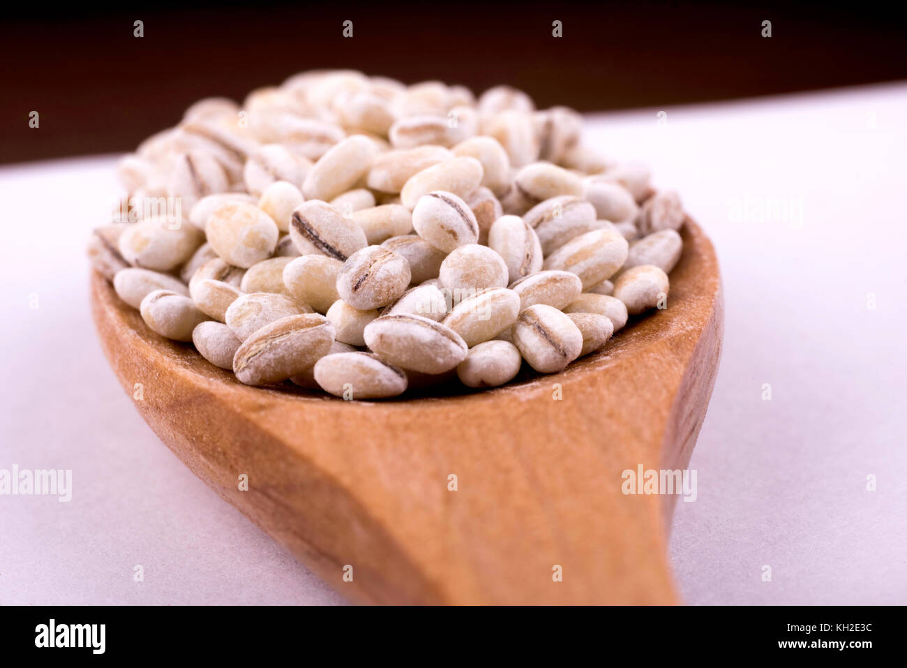 Close-up di perle di orzo su un cucchiaio di legno. Foto Stock