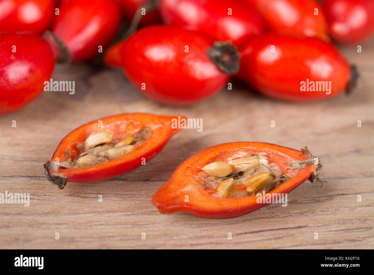 Close-up di dimezzato red rosa canina con core su sfondo di legno. due metà delle fette di frutta in radica pieno di vitamine e antiossidanti. Foto Stock