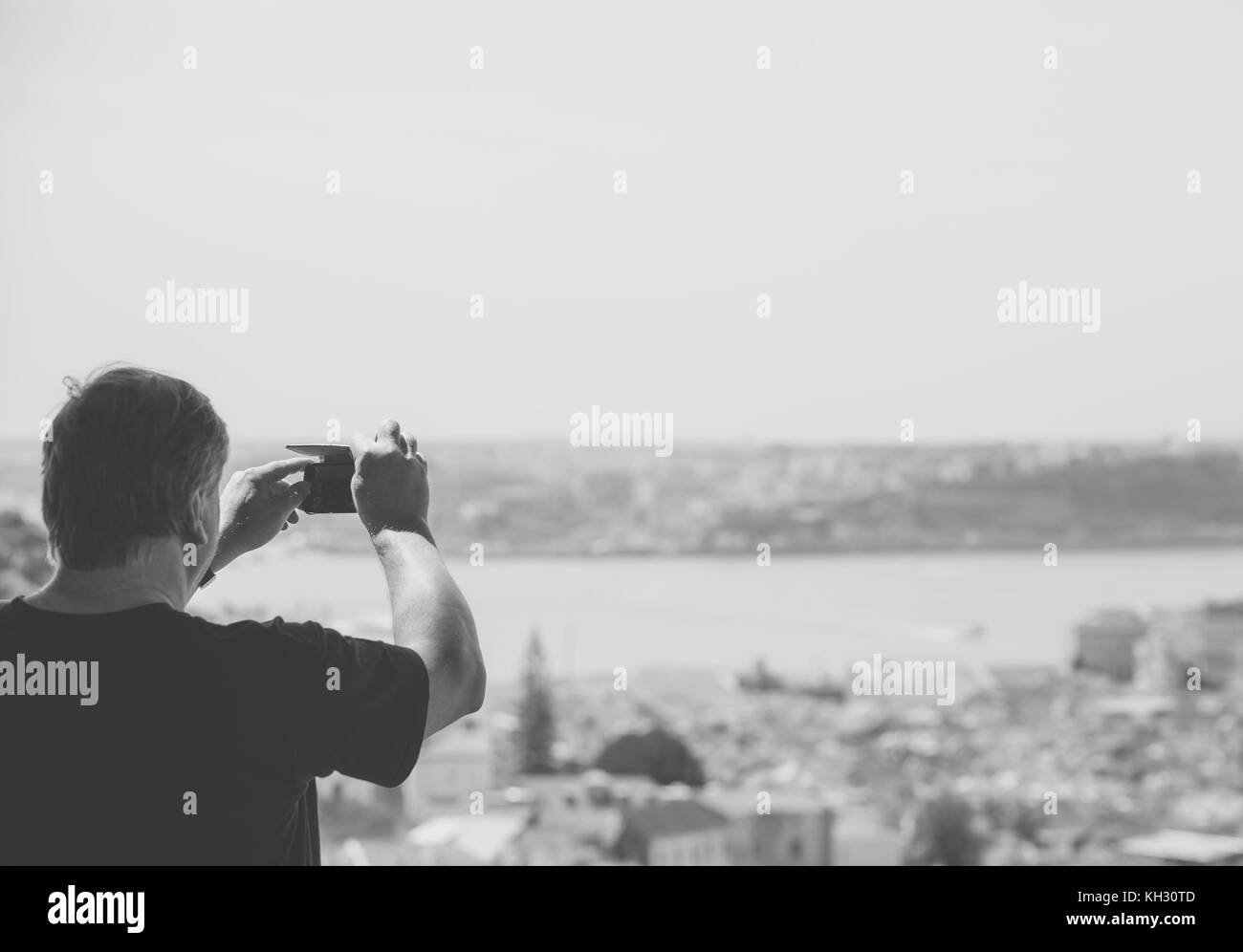 Uomo anziano che scatta foto della città vecchia. Bianco e nero. Foto Stock