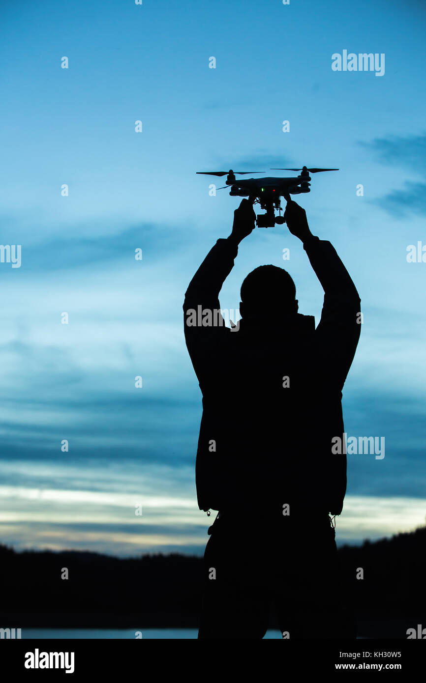 Uomo con un drone per la fotografia aerea. silhouette contro il cielo al tramonto Foto Stock