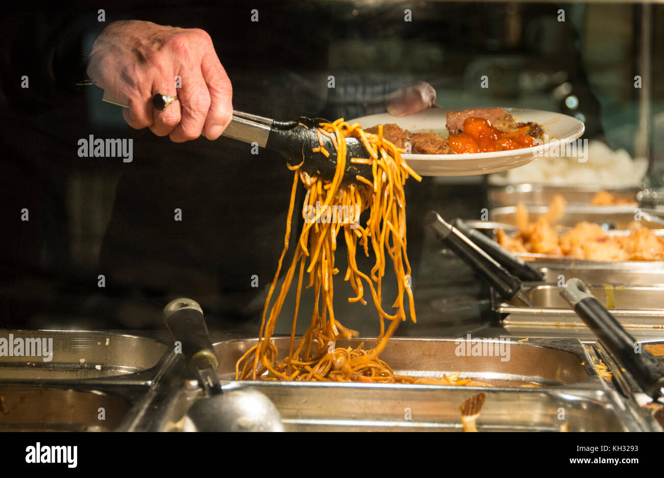 Un cliente ad aiutare se stesso al cibo in un ristorante cinese a buffet in China Town, Londra, Inghilterra, Regno Unito. Foto Stock