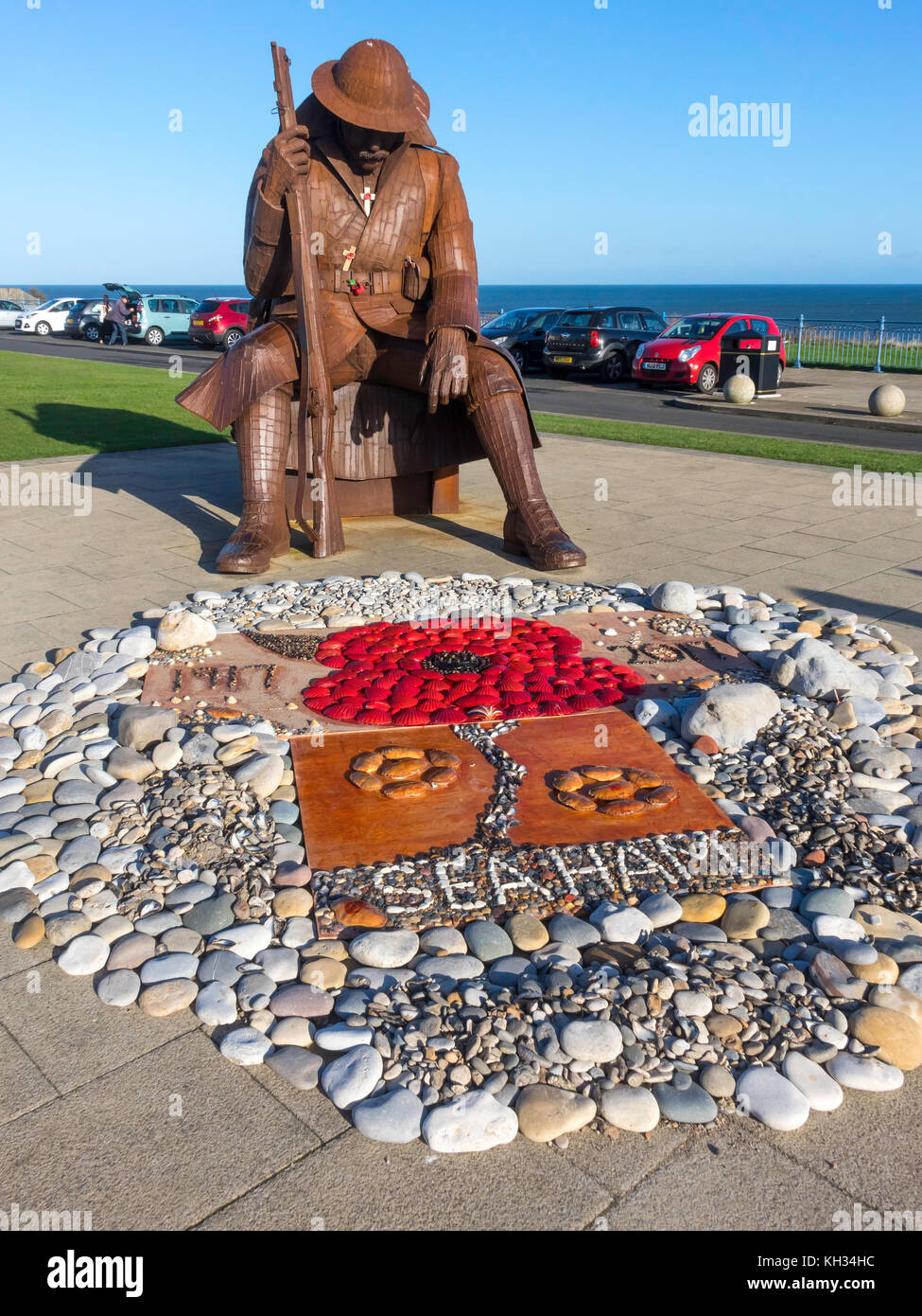 Scultura in acciaio di una prima guerra mondiale soldato a Seaham co. durham con un display di ciottoli e conchiglie di mare raffigurante un papavero per il giorno dell'Armistizio 2017 Foto Stock
