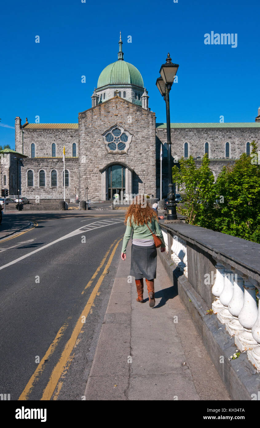 La donna irlandese sul salmone Weir Bridge a camminare verso la Cattedrale di Galway, nella contea di Galway, Irlanda Foto Stock