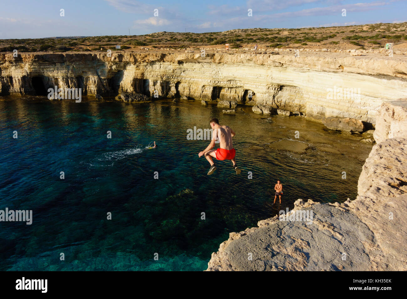 Giovane maschio salti turistica dalla scogliera, Cape Greco seacaves, Cipro Foto Stock