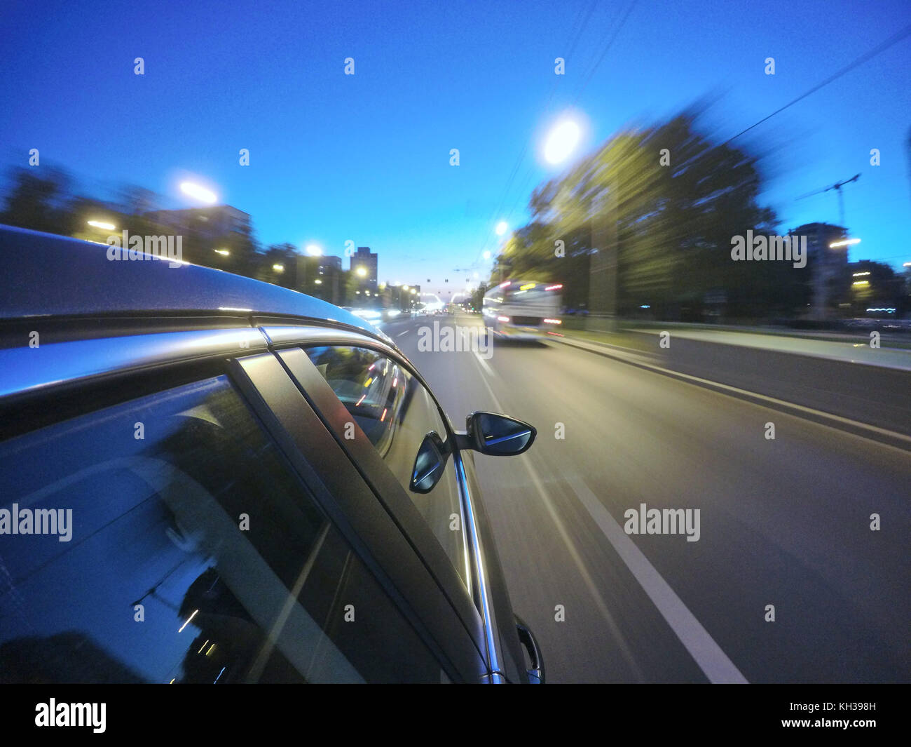 La vettura è in movimento ad alta velocità su strada di notte nella città. Lato della telecamera sul corpo vettura. Foto Stock