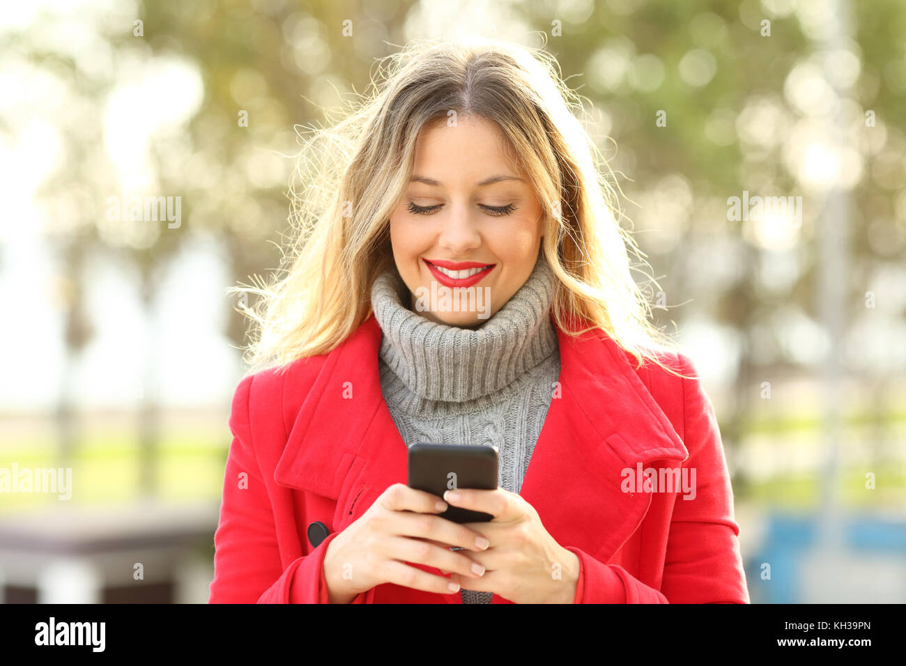 Vista frontale il ritratto di una donna che utilizza una smart phone all'aperto in un parco in inverno Foto Stock