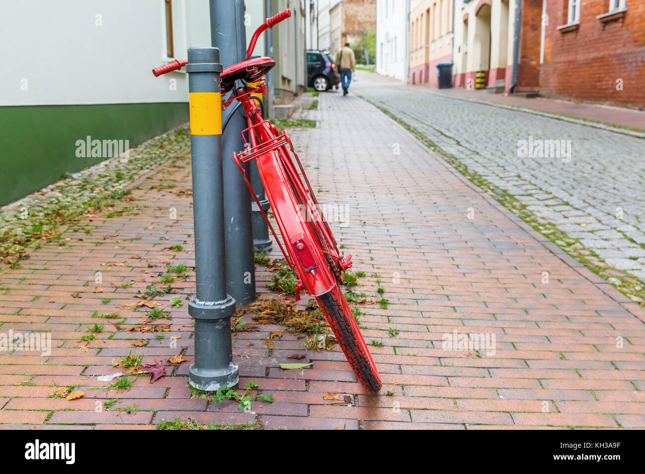 Vecchia dipinte di rosso bicicletta si appoggia contro un lampione in città Foto Stock