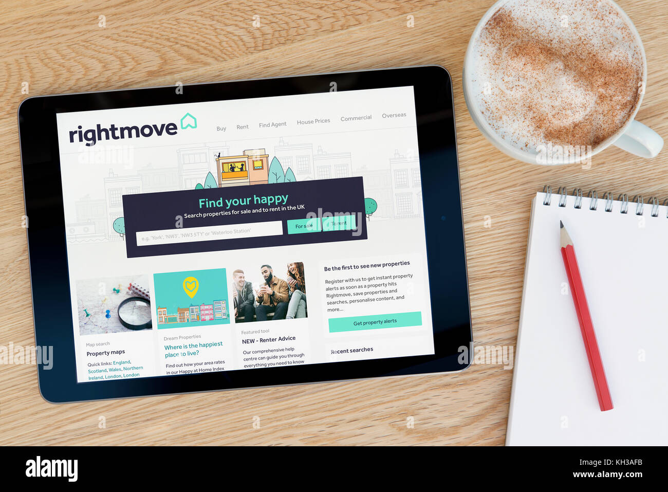 Il sito web Rightmove funzioni su un iPad dispositivo tablet pc che si appoggia su una tavola di legno accanto a un blocco note e matita e una tazza di caffè (editoriale solo) Foto Stock