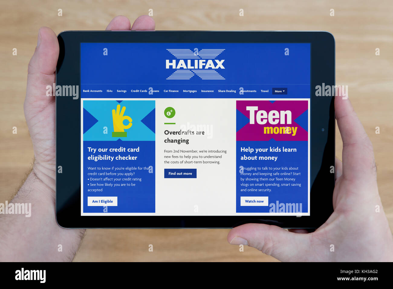 Un uomo guarda l'Halifax bank sito sul suo iPad dispositivo tablet, sparato contro un tavolo di legno top sfondo (solo uso editoriale) Foto Stock