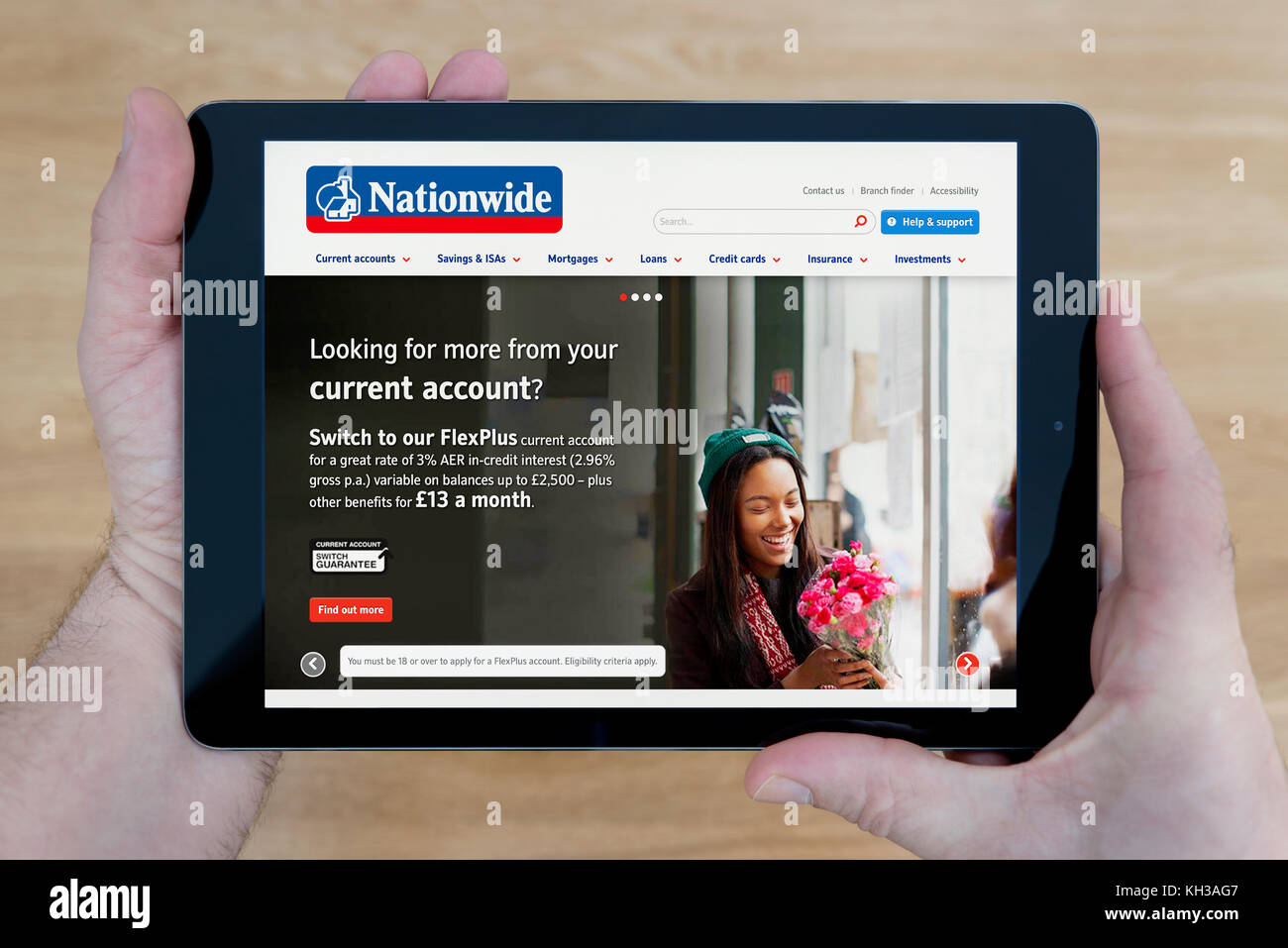 Un uomo guarda la Nationwide building society sito web sul suo iPad dispositivo tablet, sparato contro un tavolo di legno top sfondo (solo uso editoriale) Foto Stock