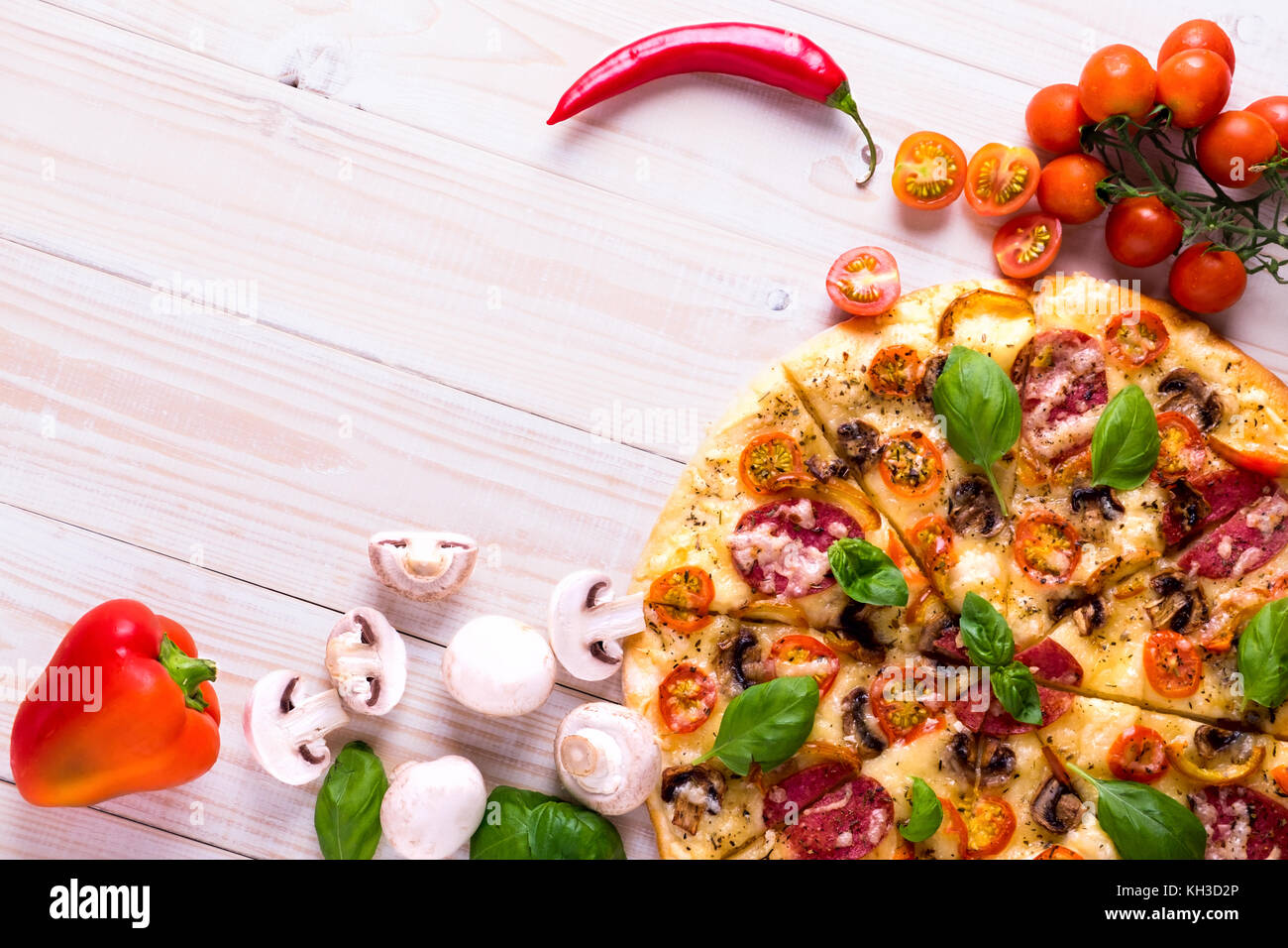Pizza con salame spezie e verdure su un bianco sullo sfondo di legno con spazio di copia Foto Stock