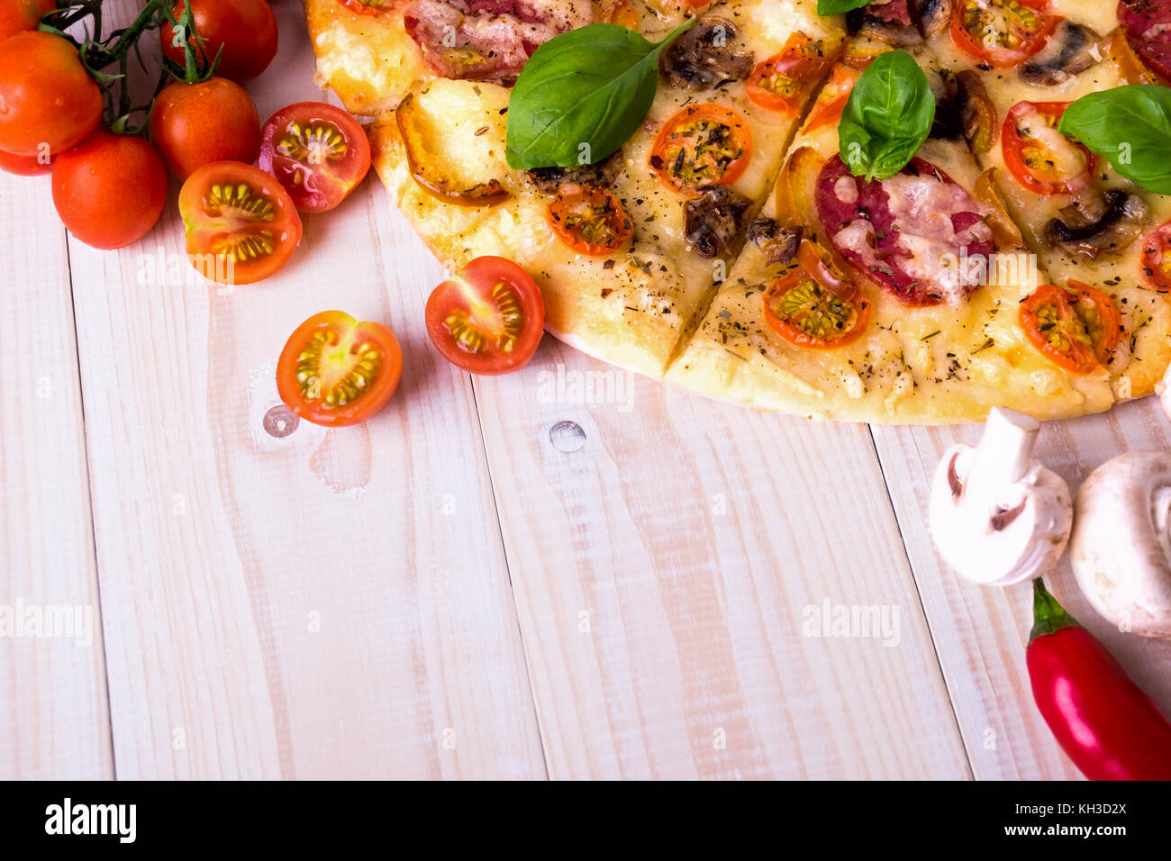 Pizza con salame spezie e verdure su un bianco sullo sfondo di legno con spazio di copia Foto Stock