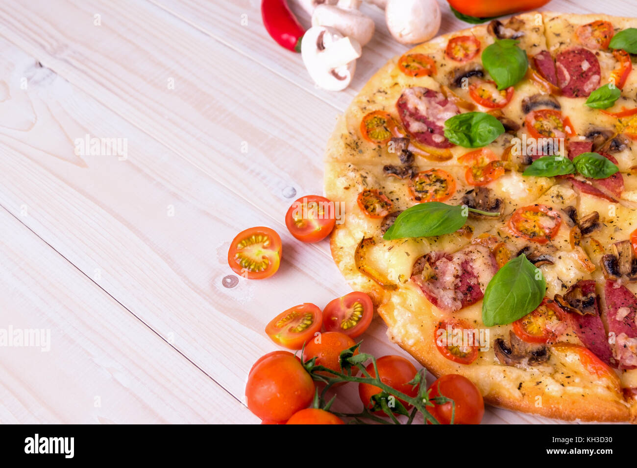 Pizza con salame spezie e verdure su un bianco sullo sfondo di legno con copia spazio. Foto Stock