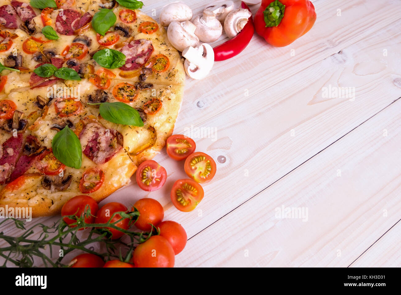 Pizza con salame spezie e verdure su un bianco sullo sfondo di legno con spazio di copia Foto Stock
